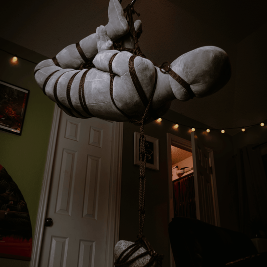 Shibari practice doll in a rope suspension
