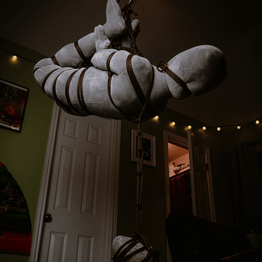 Shibari practice doll in a rope suspension